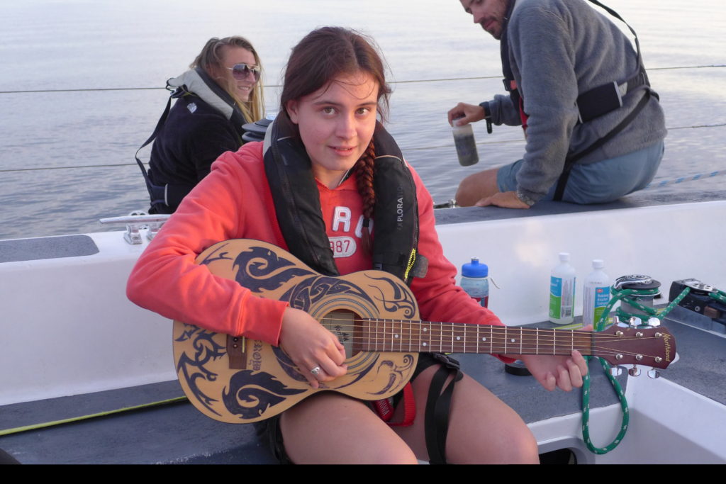 Olivia tries out Andrew's guitar on deck during one of the most beautiful sunsets imaginable!